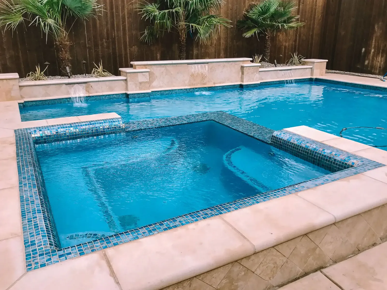 Raised spa with blue glass tile and stone coping